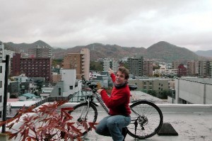 My bicycle and me on my host's roof and Sapporo's ski-jum in the background